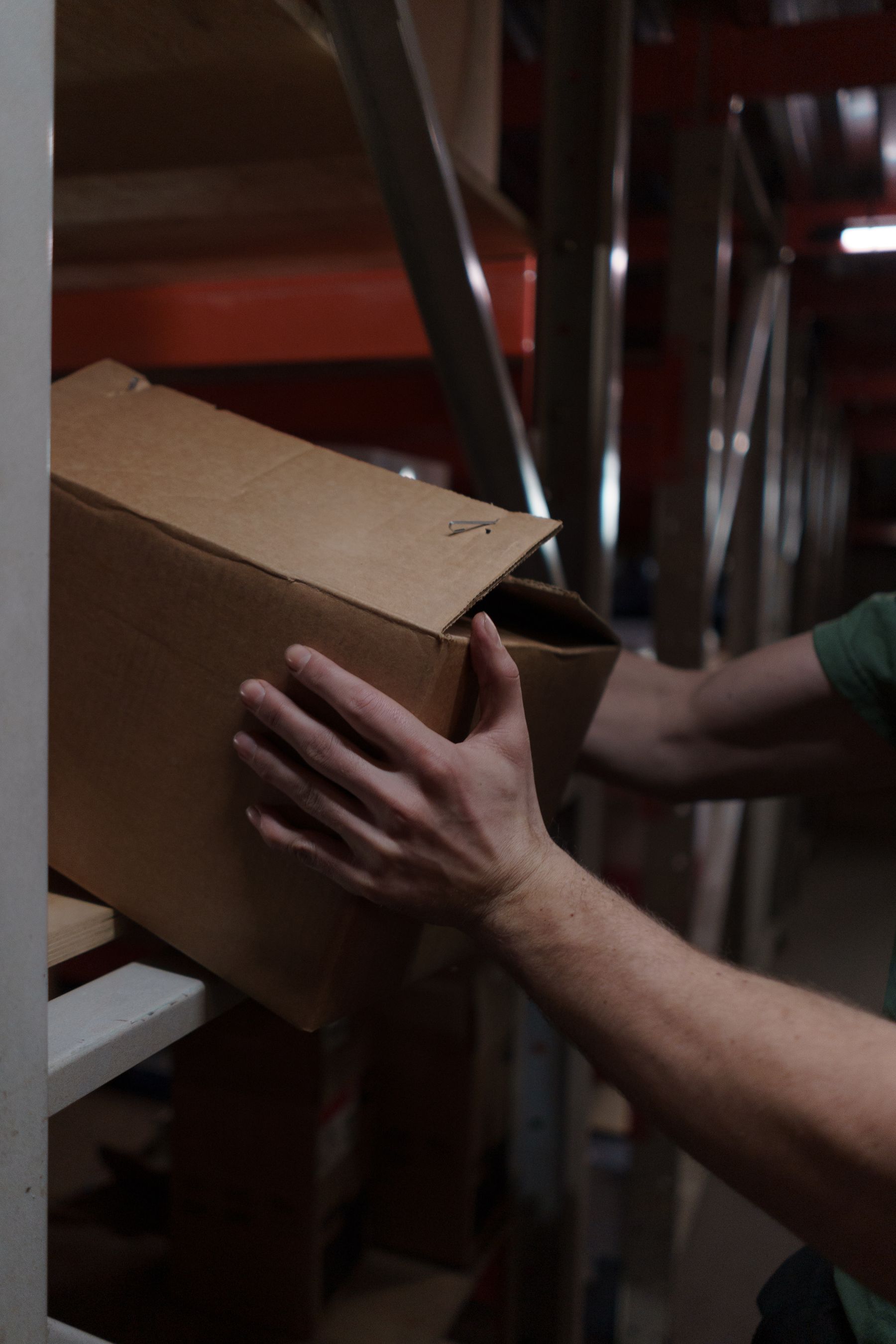 Warehouse worker placing a plain cardboard box onto a storage shelf